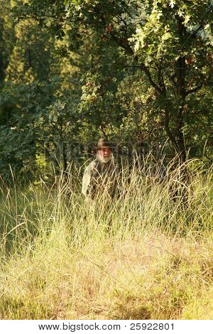 un cacciatore si nasconde nel bosco cercando di trovare e sparare un mostro di Sasquatch