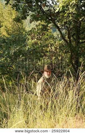 un cacciatore si nasconde nel bosco cercando di trovare e sparare un mostro di Sasquatch