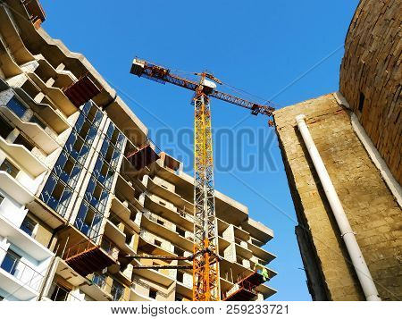 Crane And Building Construction Site Against Blue Sky. Construction Crane Near Building.