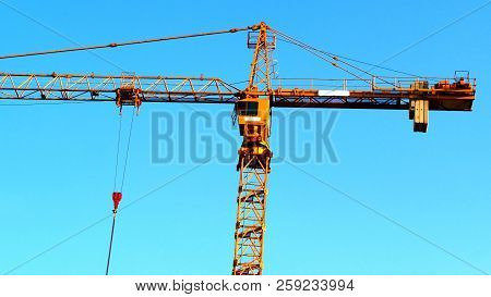 Building Crane Against Blue Sky. Hoisting Crane. Construction Site. Industrial Crane.