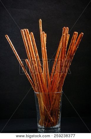 Pretzel Sticks In Small Glass On Black Background