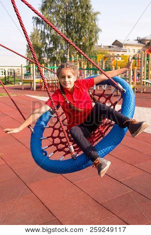 Happy Laughing Child Swinging On A Swing With Arms Outstretched At Playground In Summer, Vertical