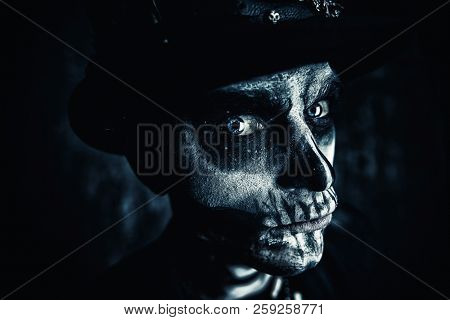 Close-up portrait of a man with a skull makeup dressed in a tail-coat and a top-hat. Baron Saturday. Baron Samedi. Dia de los muertos. Day of The Dead. Halloween.