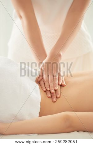 Unrecognizable Woman Putting Pressure On Loin Of Female Client During Massage Session In Spa Salon