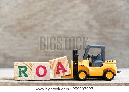 Toy Forklift Hold Letter Block  In Word Roa (abbreviation Of Return On Assets) On Wood Background