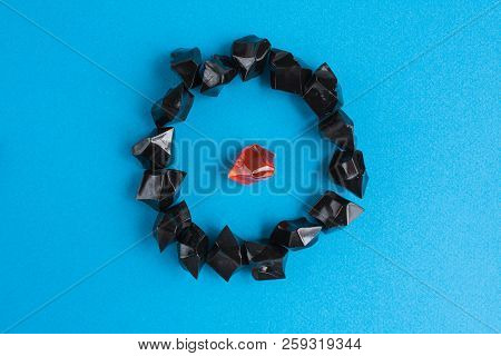 One Orange Plastic Gem Surrounded By Black On A Blue Background