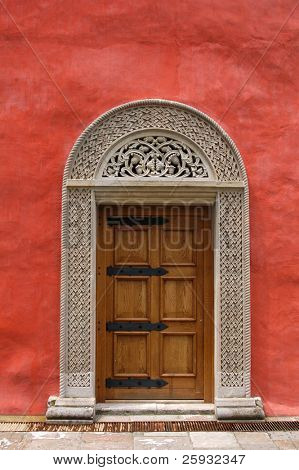 Porta di pietra medievale scolpita nel muro rosso stucco nel monastero di Zica, Serbia