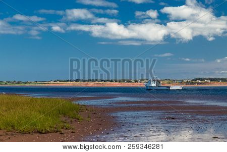 Lobster fishing boat sailing past sandy beaches in rural Prince Edward Island, Canada.