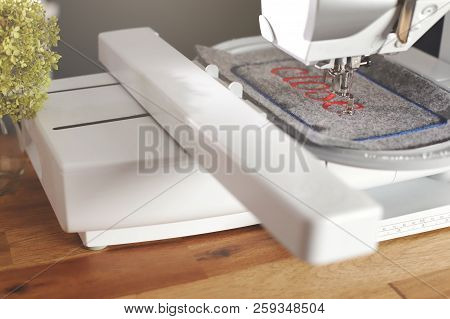 Diagonal View On A Modern Computerised Sewing Machine With Embroidery Unit Stitching Red Lettering O