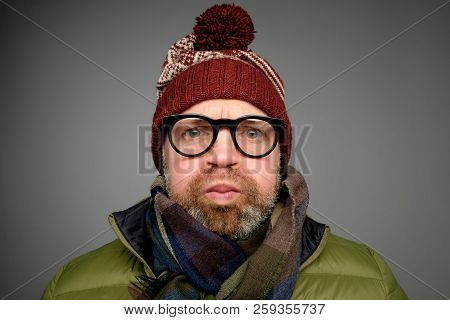 Mature Funny Man In Warm Clothes And Glasses Blowing His Cheeks While Being Offended At Somebody