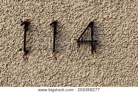 Old Grungy White Rock Wall With The Numbers 114 Hastily Glued With Runny Adhesive