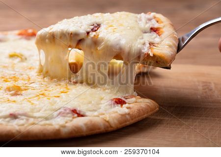 Close-up Of A Delicious Cheesy Pizza On Wooden Table