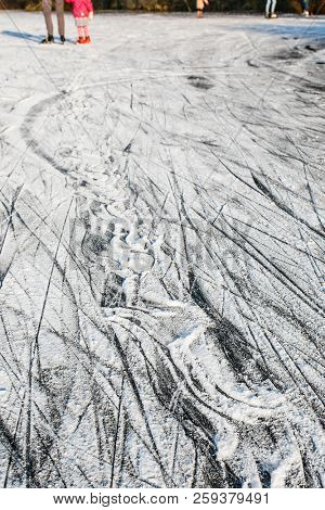 Surface of outdoor ice with snow, replete with skate marks. Ice background with skaters