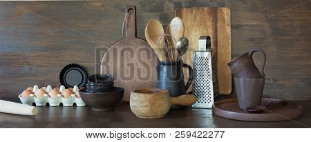 Crockery, Clayware, Dark Utensils And Other Different Stuff On Wooden Tabletop. Kitchen Still Life A