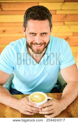 Cafe Visitor Happy Face Enjoy Coffee Caffeine Drink. Man Bearded Guy Drinks Cappuccino At Wooden Tab