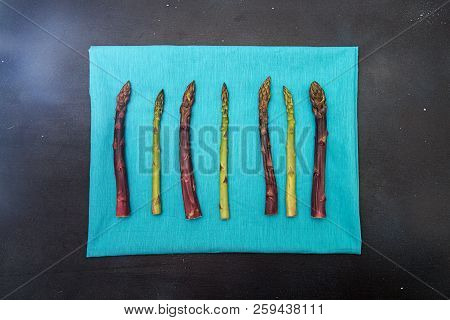 Background Flat Lay Green Purple Asparagus On Blue. Frame Black Surface. Overhead.copy Space.