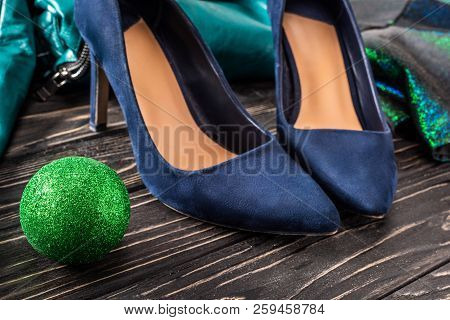 Close Up View Of Bright Feminine Blue Shoes And Green Chirstmas Ball On Wooden Surface