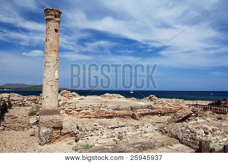 Antiche rovine di sarde di Nora con mare, nave e faro