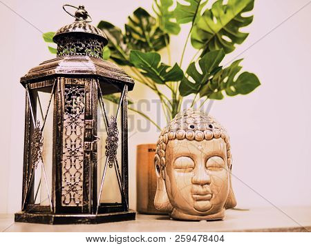 Buddah Statue In Modern Home, Home Decoration. Candle Lighter And Buddha Head Statue And Monstera's 