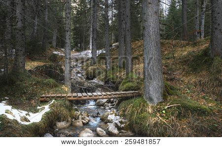 Picturesque Landscape With A Small Alpine River And A Rustic Wooden Bridge, In The Forests Of Alps M