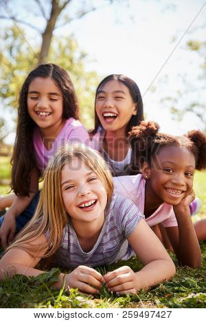 Four schoolgirls lying on each other in a field, close up