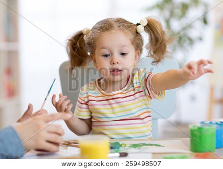 Cute Child Toddler Girl In Striped Shirt And Pony Tails Paints In The Art Class