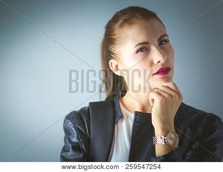 Portrait Of Beautiful Young Brunette Woman In Stylish Black Jacket On Gray.