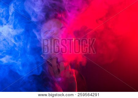 Young Woman Smoking Vape Or E-cigarette In Neon Light