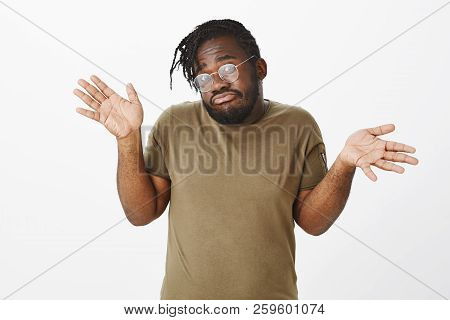 He Knows Nothing. Portrait Of Unaware Clueless Cute African-american Brother In Olive T-shirt And Gl