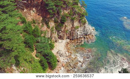 Beautiful View Of The Peninsula And A Small Rocky Island. Seaside Landscape With Coniferous Forest. 