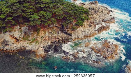 Beautiful View Of The Peninsula And A Small Rocky Island. Seaside Landscape With Coniferous Forest. 