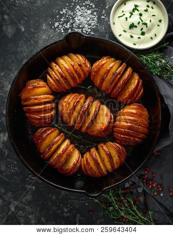 Hasselback Baked Potatoes Served In Cast-iron Pan With Sour Cream Salt, Pepper And Herbs