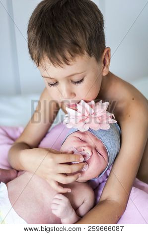 Cute Caucasian Pre-school Age 6 Year Old Child Comforting His Newborn Baby Sister Crying. He Gives H