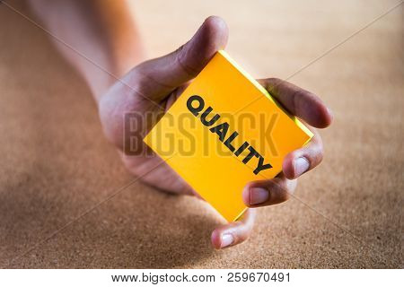 A Hand Holding A Colored Paper Note With The Word Quality
