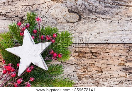 White Wooden Christmas Star With Fir Tree Branch And Red Berries On Rustic Wood Background