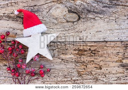 Christmas Star With Santa Hat And Red Berries On Wooden Background