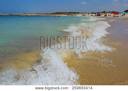 People Rest On The Beach Nahsholim, Haifa Area, Israel, In The Foreground Wave Runs Ashore