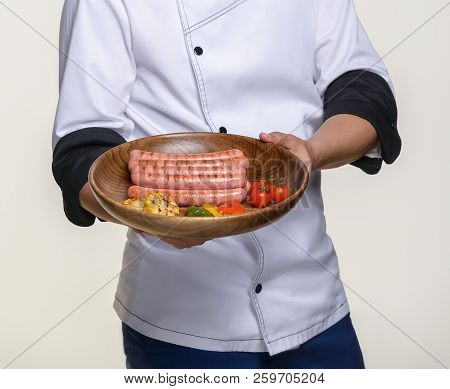 The Cook Holds A Ready-made Dish Of Fried Sausages