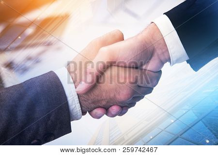 Close Up Of Two Businessmen Shaking Hands Over A Cityscape Background. Sealing A Deal And Corporate 