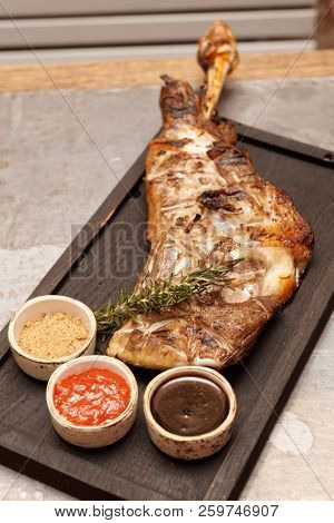 Braised and grilled leg of lamb with sauces on restaurant table