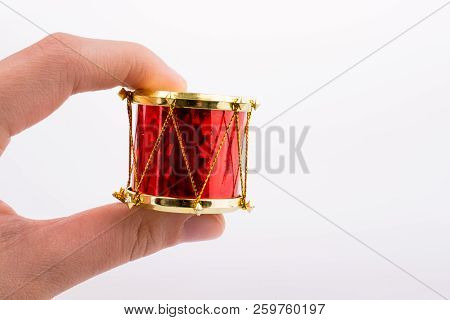 Hand Holding A Small Drum On A White Background