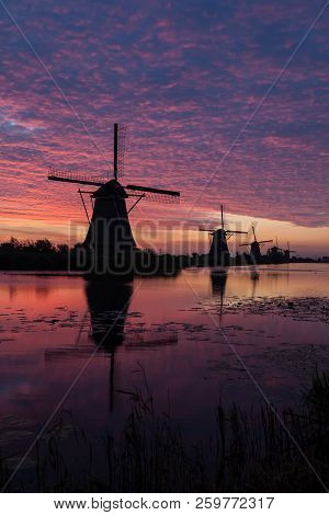 On The Water There Are Several Windmills In Kinderdijk In Holland By Sunrise