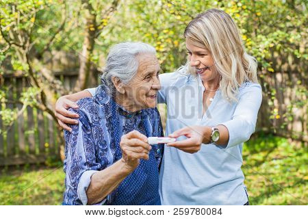 Happy Woman Expecting A Baby, Holding Pregnancy Test, Spending Time With Future Great-grandmother