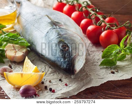 Whole Fresh Tuna With сherry Tomatoes, Lemon, Herbs, Garlic And Spices On Baking Paper On Wooden Bac