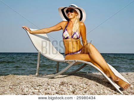 La ragazza in un cappello avendo un resto su seacoast