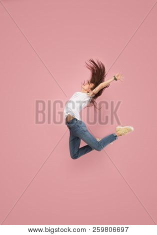I Am Happy. Mid-air Shot Of Pretty Smiling Young Woman Jumping And Gesturing Against Pink Studio Bac