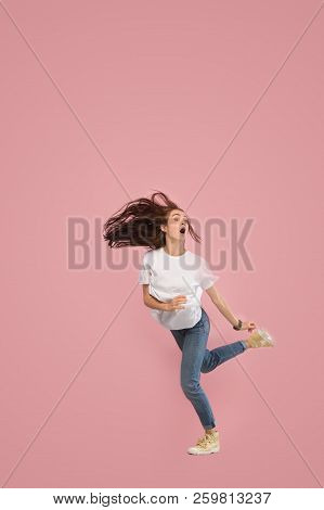 Freedom In Moving. Mid-air Shot Of Pretty Frightened Running Away Young Woman Jumping Against Pink S