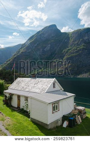 Aurlandsfjord, Flam, Norway - 27 July, 2018: High Angle View Of Cozy White House And Majestic Mounta