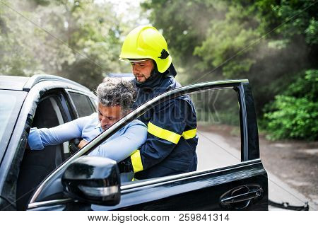 A Firefighter Getting An Unconscious Man Out Of The Car After An Accident.