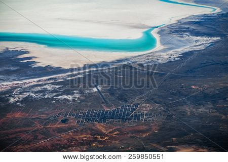 Aerial view of the town of Uyuni, Bolivia. Entrance to the Uyuni Salt Flat is visible on upper part of the frame as dark radial tracks on white salt surface.